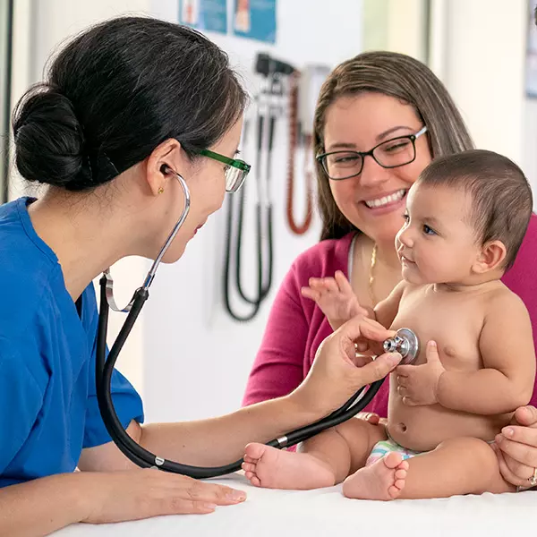 Pediatrician examines baby as mother looks on